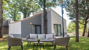 Un espacio al aire libre moderno con mobiliario de mimbre, una mesita y una planta en maceta.