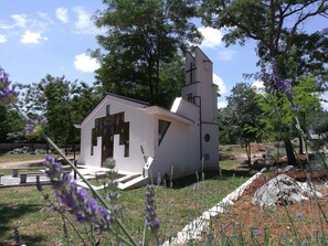 A small white church with a cross on the tower, surrounded by trees and purple flowers. - FoRest Village Resort (Citluk)