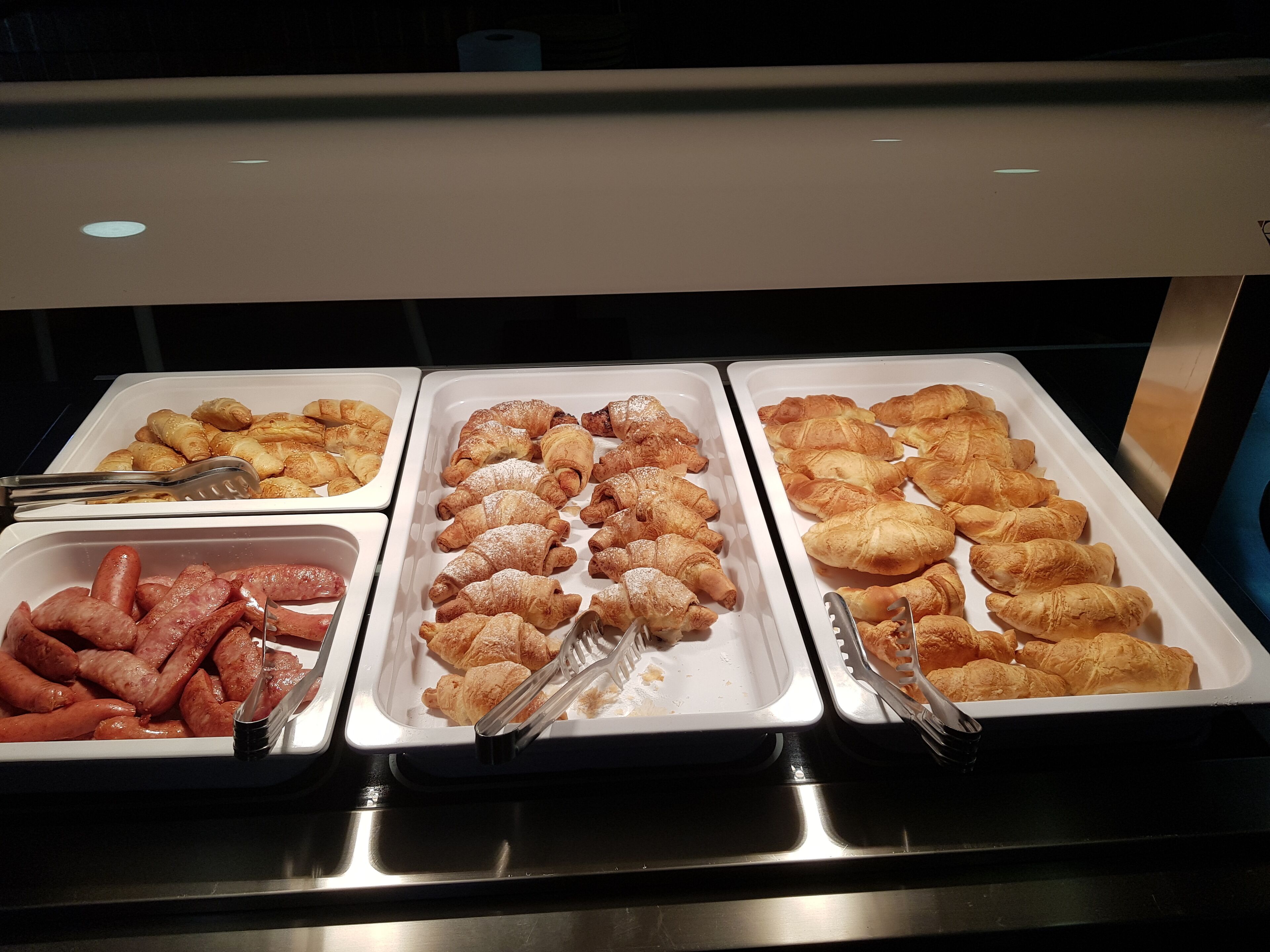 Ein Buffet mit Tabletts voller Gebäck, Wurstwaren und weiteren Speisen.