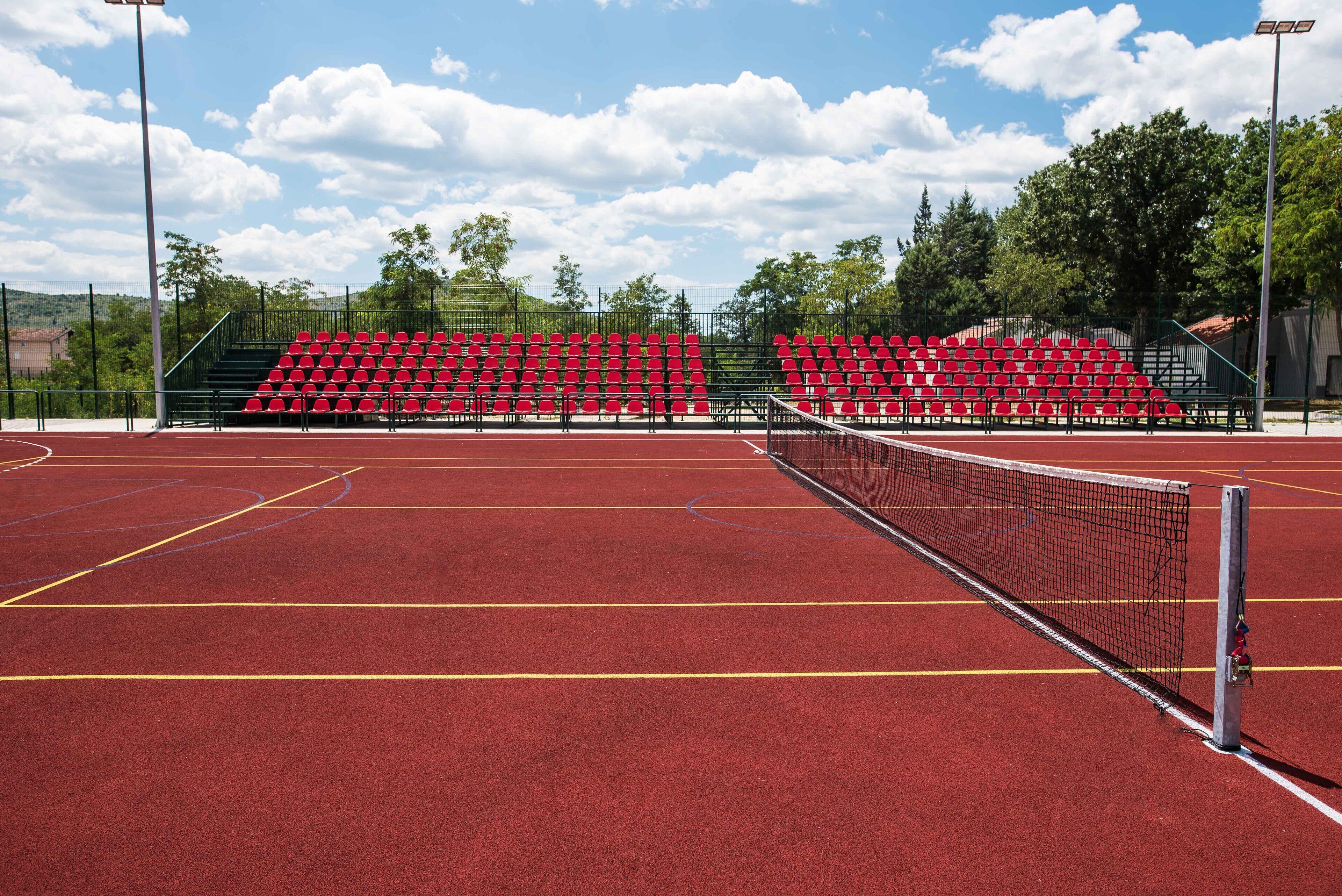 En tennisbane med røde siddepladser og net.
