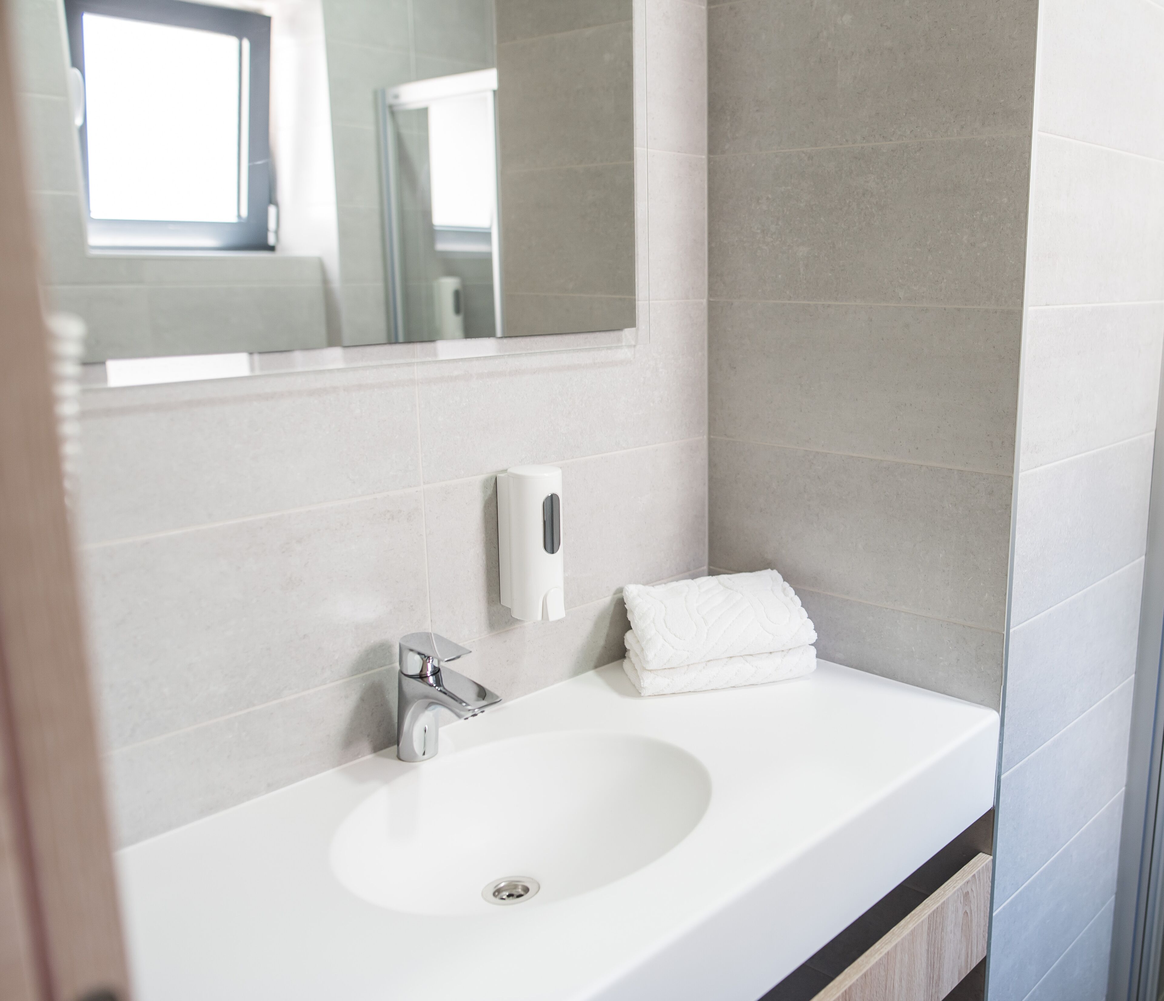 A modern bathroom with a white sink, a mirror, and a towel.