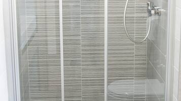 A modern bathroom with a glass-enclosed shower, a toilet, and a tiled floor.