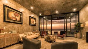 A modern living room with a large window, a sofa, a coffee table, and a fireplace.