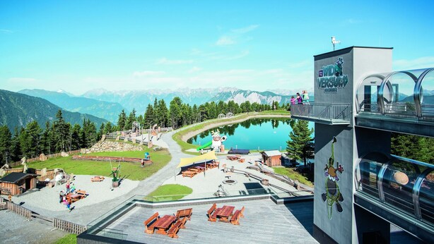 Un complexe hôtelier situé au bord d’un lac, doté d’une terrasse, d’une piscine et offrant une vue sur les montagnes.
