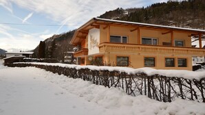 Un bâtiment à deux étages doté d’un balcon, entouré d’un paysage enneigé et d’arbres.