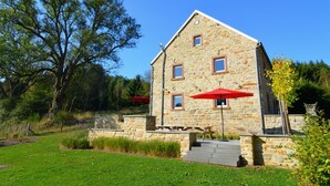 A stone building with a sloped roof, a small porch, and two red umbrellas. - Pet-friendly villa in Ondenval (Ondenval)