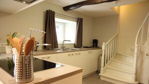 A kitchen with a modern design, featuring a built-in stove, a sink, and a window with curtains. There is a staircase leading to another level. - Pet-friendly villa in Ondenval (Ondenval)