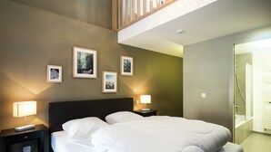 Una habitación de hotel con una cama grande, dos mesitas de noche con lámparas y cuadros enmarcados en la pared.