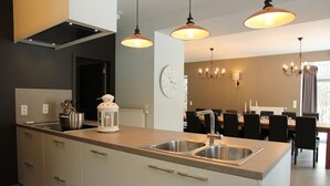 Una cocina moderna con una isla central, lavamanos dobles e iluminación colgante.