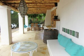 Relax on the patio with a sofa, table, and chairs, surrounded by a rustic wooden ceiling and lanterns.