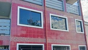 Un edificio a più piani con pareti in tegole rosse, ampie finestre e un balcone.