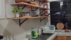 Una cucina con scaffali in legno, un lavello e diversi oggetti da cucina.