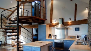 A modern kitchen with a central island, built-in oven, and a spiral staircase. - Holiday Home in Verviers with Sauna & Fireplace (Ensival)