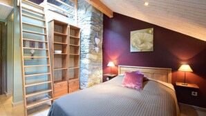 A bedroom with a bed, a wooden ladder, a stone wall, and a painting on the wall. - Renovated Mill in Bastogne near Waterfall (Bastogne)