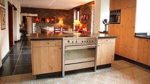 A kitchen with a central island, wooden cabinets, a built-in oven, and a stone accent wall.