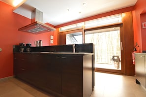 Una cocina con una isla central, estufa y ventana con vista a árboles.