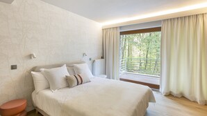 Un dormitorio con cama, mesita de noche, radiador y ventana con cortinas.