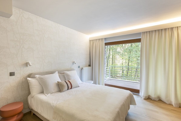 Ein Schlafzimmer mit einem Bett, einem Nachttisch, einem Heizkörper und einem Fenster mit Vorhängen.
