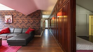 Un moderno vestíbulo de hotel con un sofá de cuero, un muro con diseño y un pasillo de madera que conduce a una habitación.