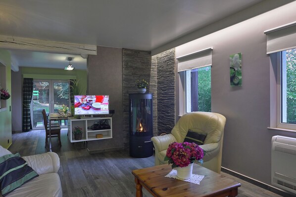 A living room with a fireplace, a television, a sofa, a dining table, and a chair.