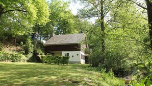 Ein rustikales Haus mit Ziegeldach, umgeben von üppiger Vegetation und einem gepflegten Rasen.