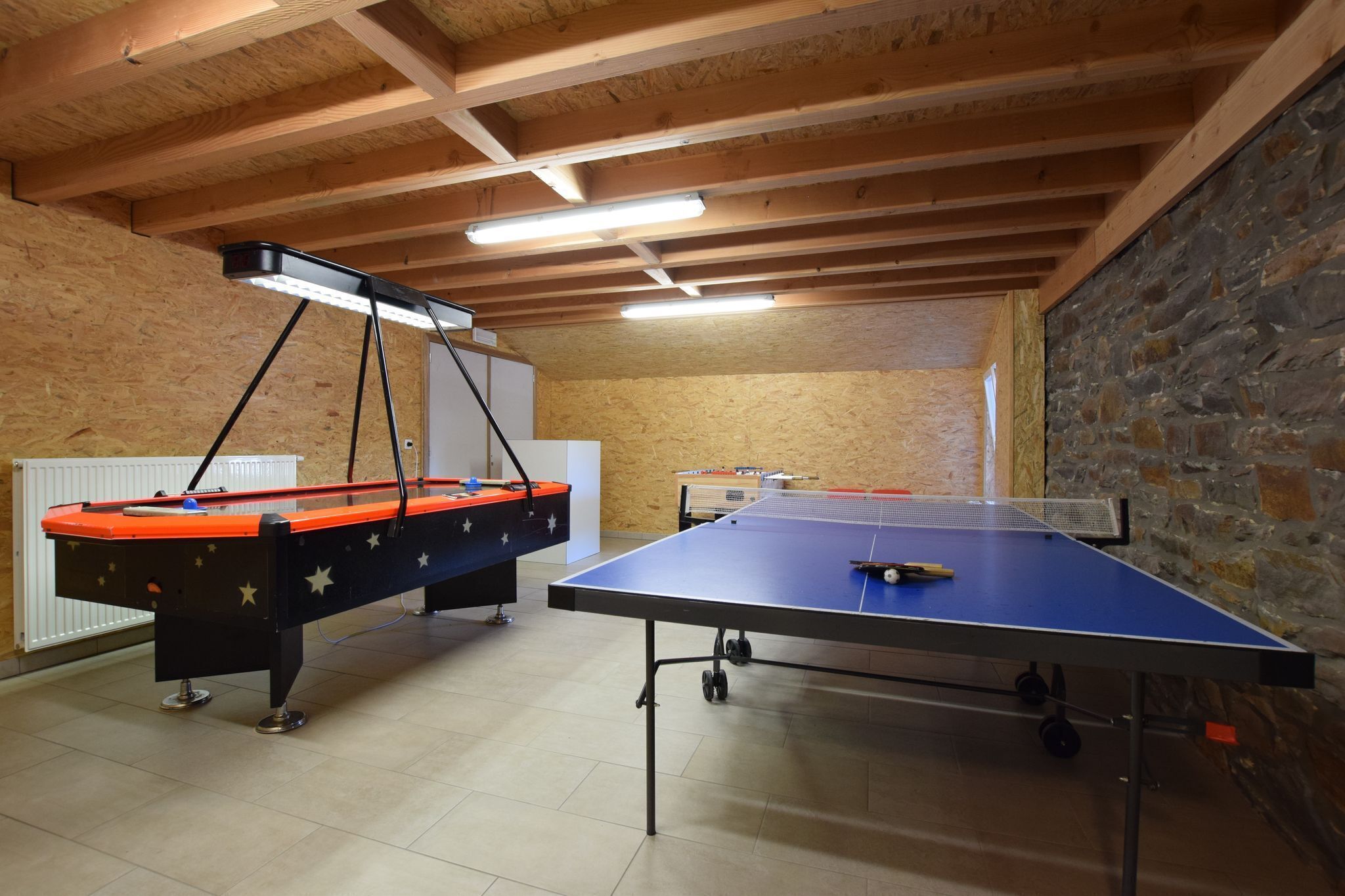 Una habitación con mesa de ping pong, mesa de fútbol de mesa y mesa de billar.