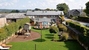 A residential area with a house featuring a large front yard, a swing set, and a small garden. - Holiday Home in Ardennes with Sauna & Pool (Vielsalm)
