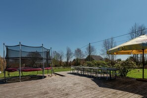 A wooden deck with a trampoline and outdoor seating area. - Comfy home near the forest with sauna (Waimes)