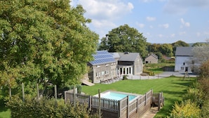 Une propriété résidentielle dotée d’une piscine, de panneaux solaires et d’une pelouse bien entretenue.