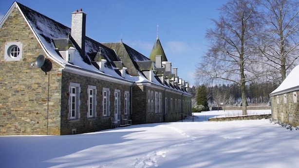 A stone building with multiple chimneys and a snow-covered landscape. - Le Hameau du Château – Elegance and serenity (Libin)