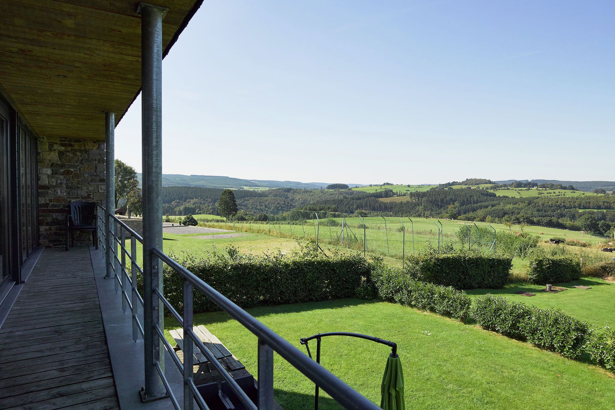 A balcony with a view of a green landscape and distant hills.
