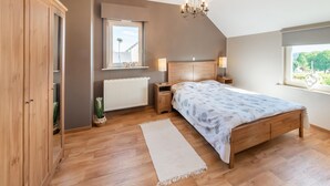 Un dormitorio con cama de madera, un radiador, una ventana con vistas y una araña.