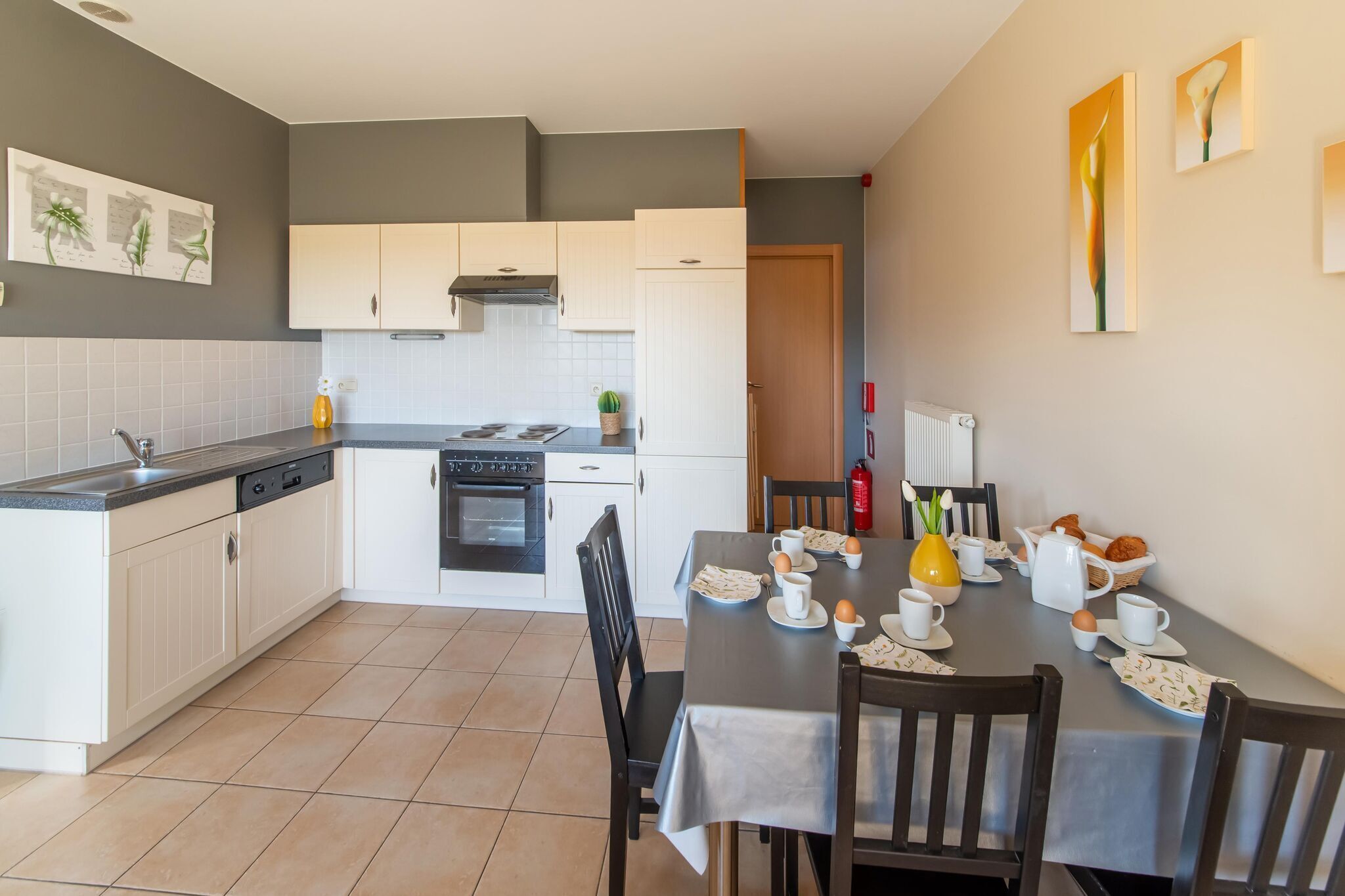 Een kleine keuken met witte kastjes, een fornuis en een ontbijttafel.