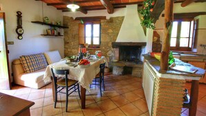 A rustic dining area with a stone fireplace, wooden beams, and a table set for a meal.
