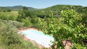 A rectangular pool surrounded by a wooden fence, set against a backdrop of lush green hills and trees. - Villa in Casentino with Pool & Castle Views (Stia)