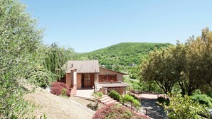 A rustic house with a tiled roof, surrounded by lush greenery and a hillside. - Villa in Casentino with Pool & Castle Views (Stia)
