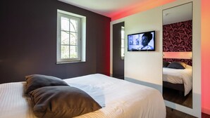A bedroom with a bed, a television, a window, and a mirror. - Holiday Home in Dalhem with Private Sauna (Aubel)