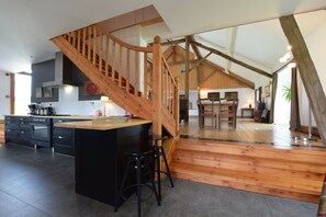 Une cuisine spacieuse avec un escalier en bois menant à une salle à manger.