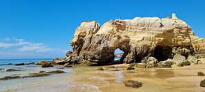 A coastal rock formation with a natural arch, sandy beach, and clear blue sky. - Vacation in the Algarve: great view of the Atlantic Ocean, 5 minutes to the beach. (Portimão)