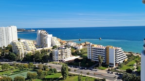 Un paisaje urbano costero con edificios modernos, un cielo azul despejado y vistas al mar.