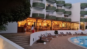 Un hotel con piscina, zona de estar al aire libre y bar.