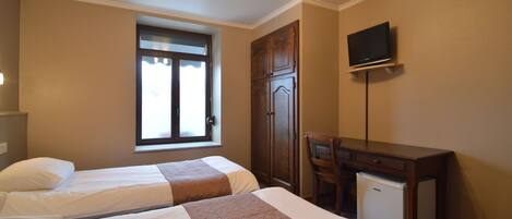 A hotel room with two beds, a desk, a television, and a small refrigerator.
