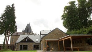 A stone building with a large lawn, a covered patio, and a tower. - Holiday Home in Stoumont near Spa Resort (Stoumont)