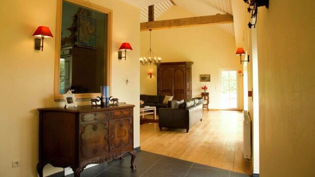 A spacious living area with a fireplace, a large mirror, and a wooden cabinet. - Holiday Home in Stoumont near Spa Resort (Stoumont)