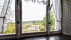 Una ventana con vistas a un pueblo, cortinas y un estampado floral en el papel tapiz.