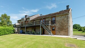 A two-story stone building with a covered patio and outdoor seating area.
