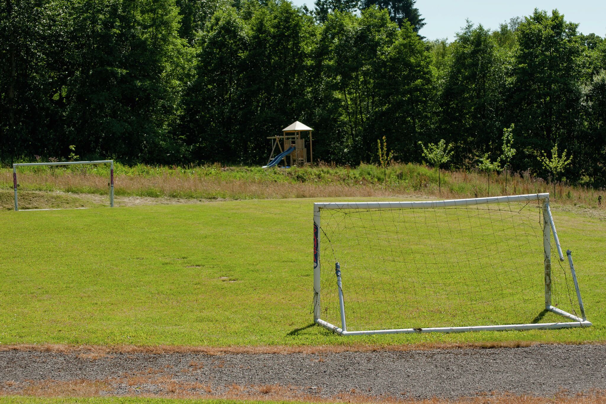 Un terrain de football avec des buts et un petit pavillon en arrière-plan.