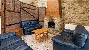 A cozy living room with a stone fireplace, leather sofas, and a wooden coffee table.