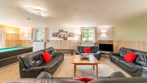 Een moderne woonkamer met leren banken, een pooltafel en een flatscreen televisie.