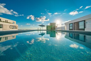 A clear swimming pool with a modern building on one side and a clear sky above. - Downtown Park by Deserve (Paphos)